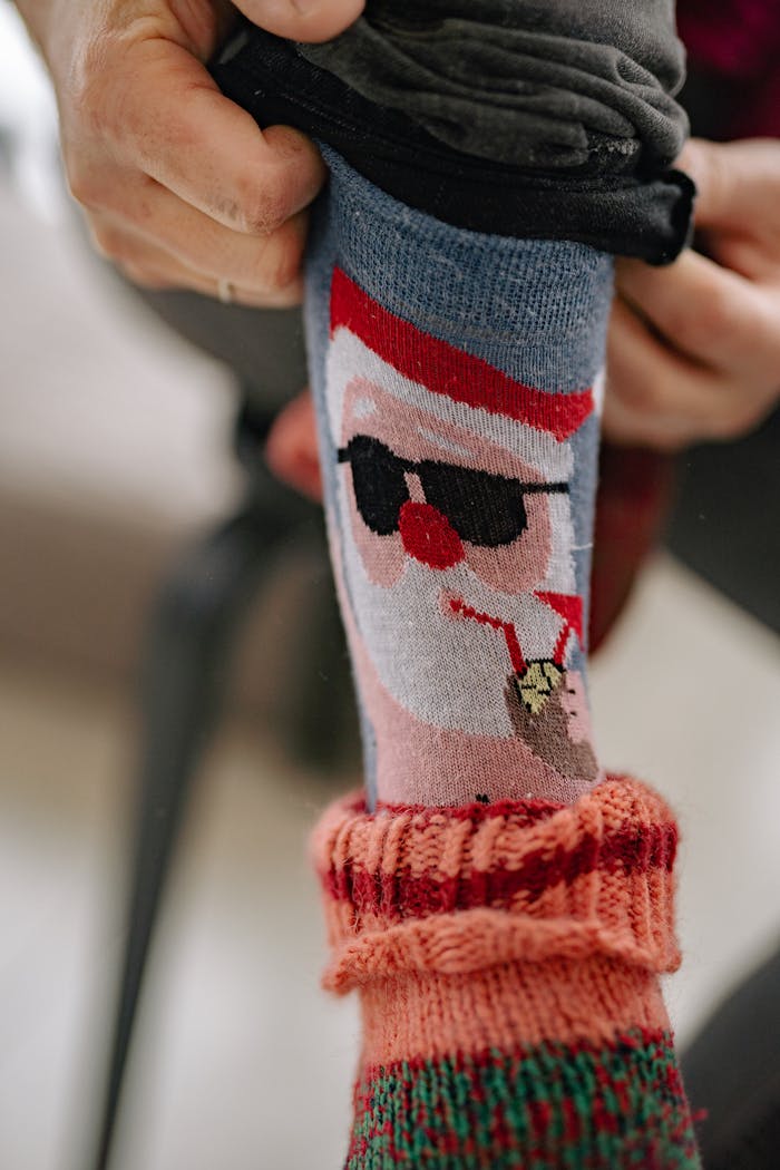 Close-up of colorful Santa-themed socks being adjusted for a warm and cozy winter look.