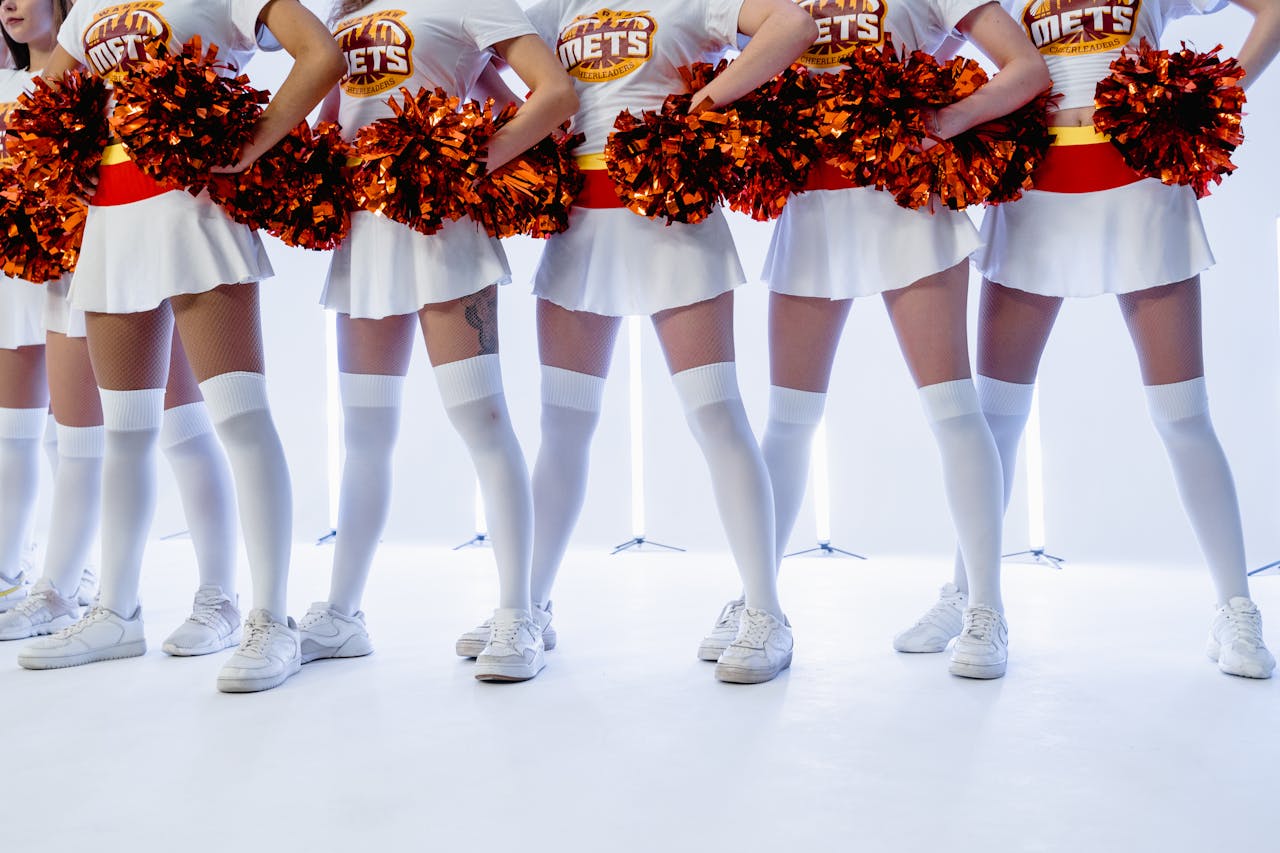 Energetic cheerleaders in uniform with orange pom poms, showcasing team spirit.
